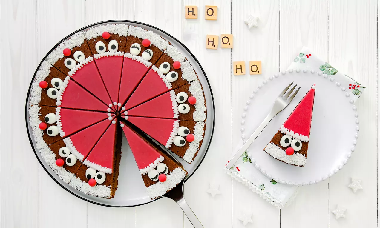 Csokoládés tortaszeletek piros marcipánréteggel, hófehér cukorkörvonallal és mókás szemekkel díszítve, ünnepi hangulatot árasztva egy fehér tányéron
